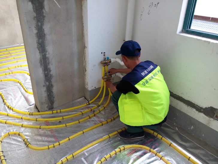 舒适100网工程服务人员正在安装地暖分集水器