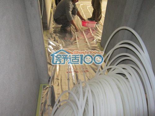 舒适100网工人正在进行地暖管材的铺设